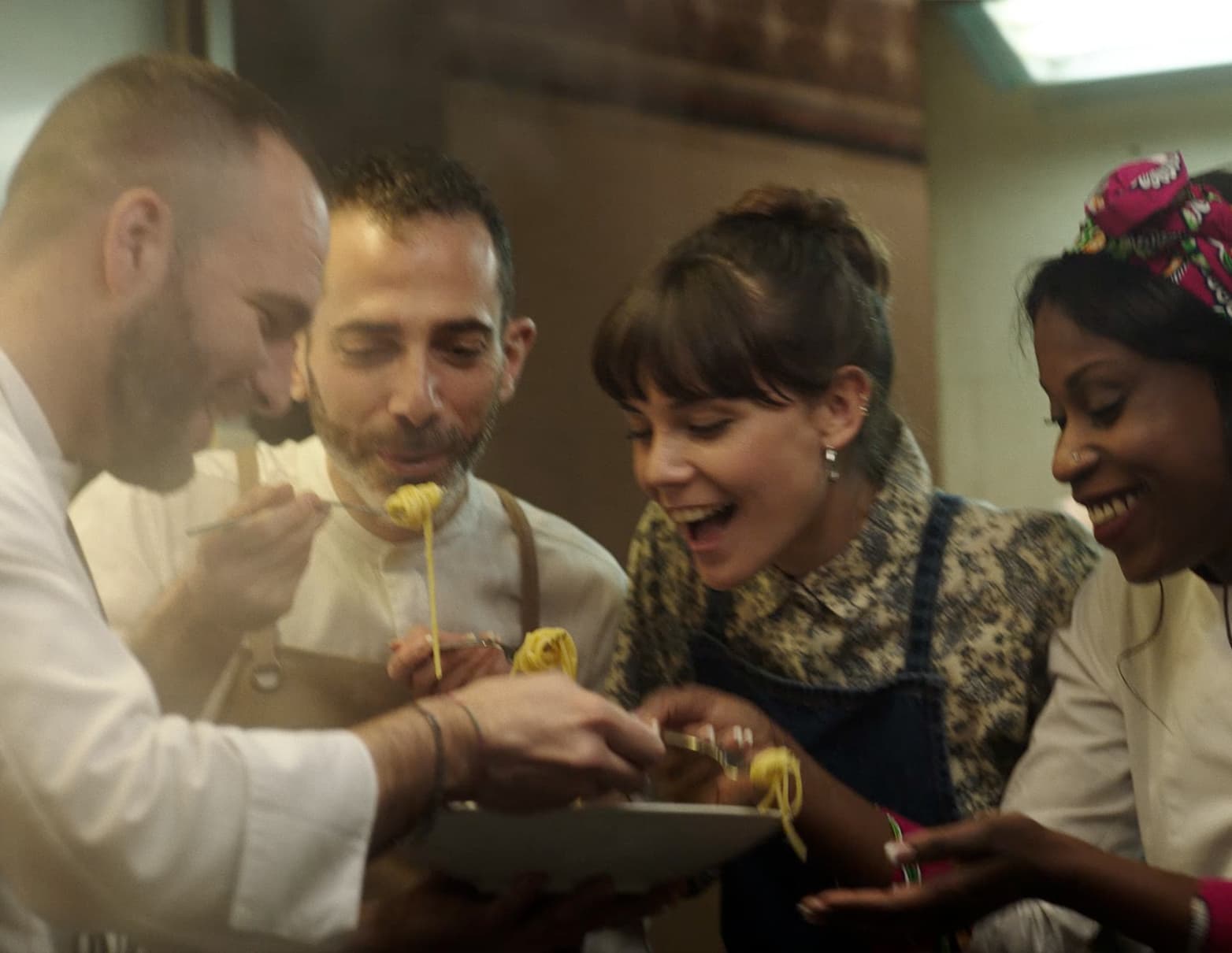 Four people tasting a pasta dish.