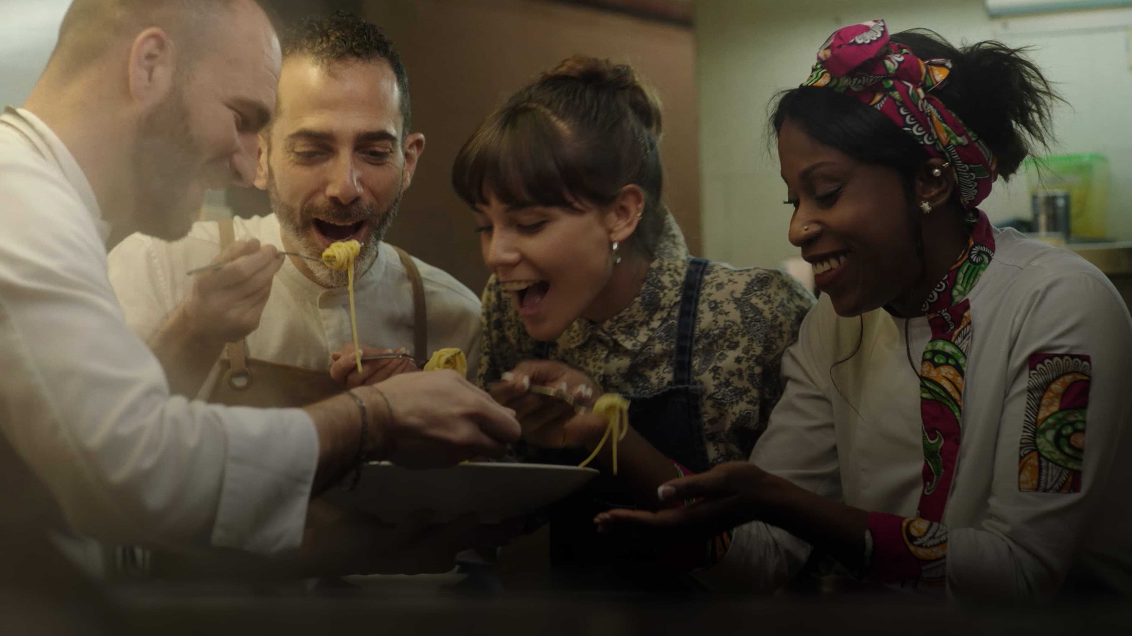 Four people tasting a pasta dish.